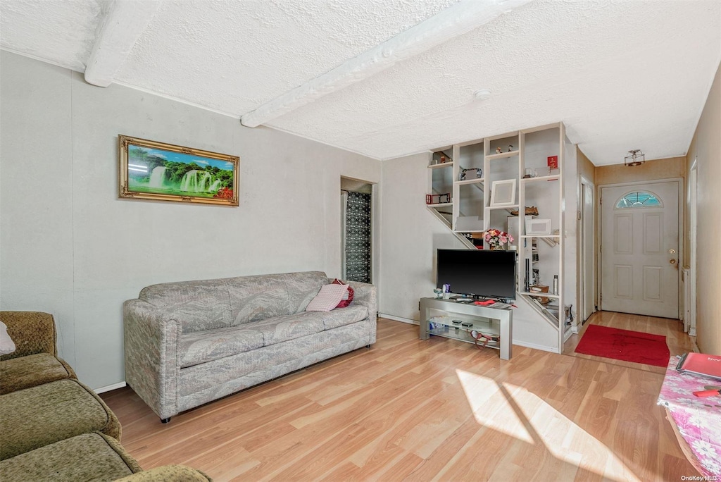 living room with wood-type flooring, beam ceiling, and a textured ceiling