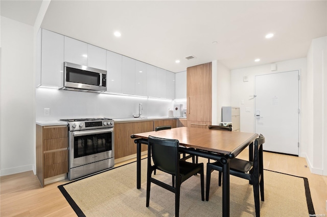 kitchen featuring white cabinetry, light hardwood / wood-style flooring, stainless steel appliances, and sink