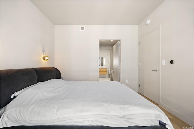 bedroom with ensuite bath and light hardwood / wood-style floors