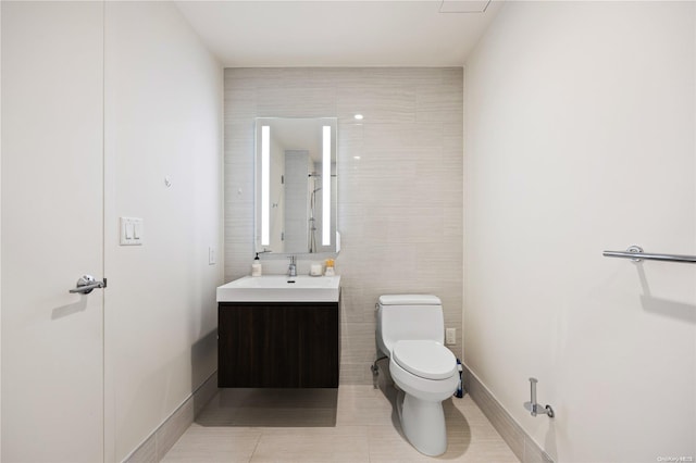 bathroom featuring tile patterned flooring, vanity, toilet, and tile walls