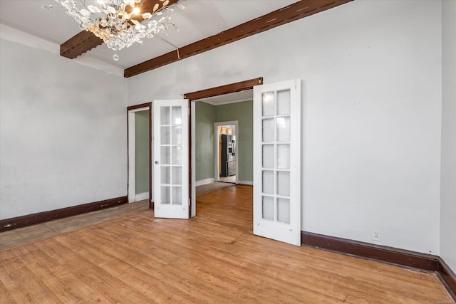 spare room featuring a notable chandelier, beam ceiling, french doors, and light hardwood / wood-style floors