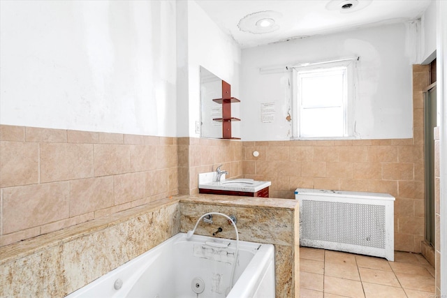 bathroom featuring radiator, tile walls, a bathing tub, tile patterned floors, and sink