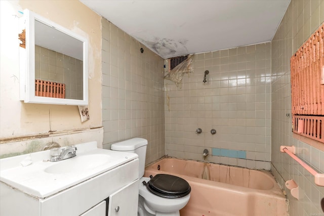 full bathroom with tile walls, tiled shower / bath, vanity, and toilet