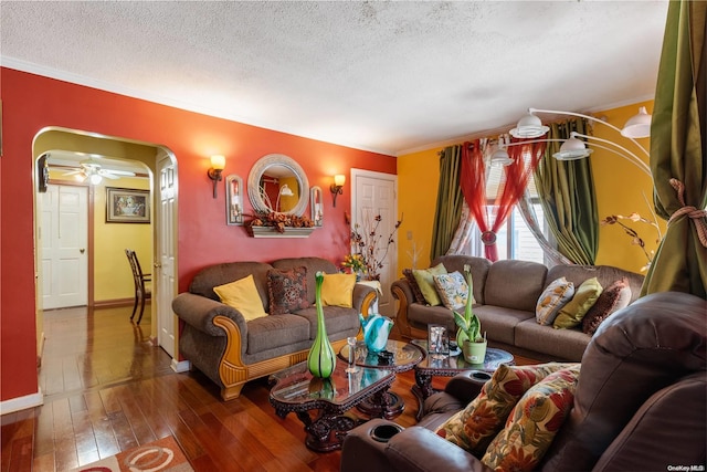 living room with crown molding, ceiling fan, dark wood-type flooring, and a textured ceiling