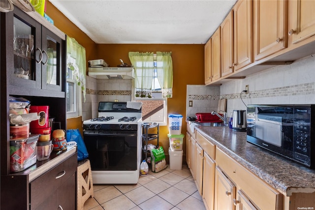 kitchen featuring backsplash, sink, light tile patterned floors, and white range with gas stovetop