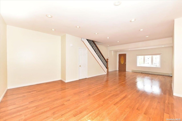 unfurnished room with a baseboard radiator and light wood-type flooring