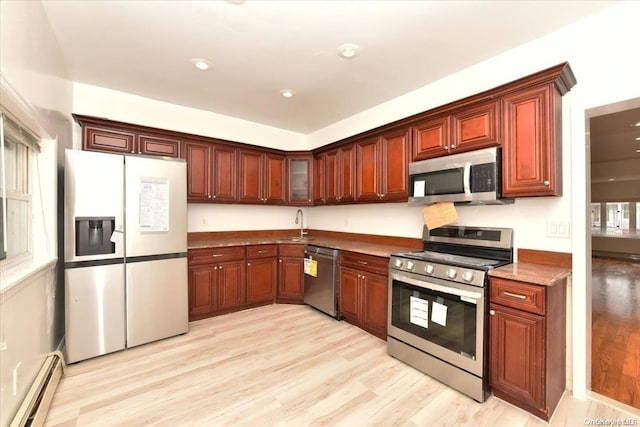 kitchen with baseboard heating, sink, stainless steel appliances, and light wood-type flooring