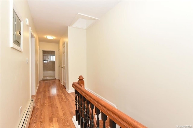 corridor with light wood-type flooring and a baseboard heating unit