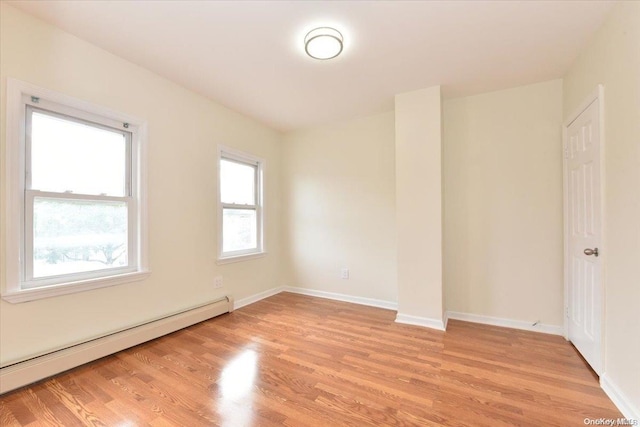 unfurnished room with baseboard heating and light hardwood / wood-style flooring