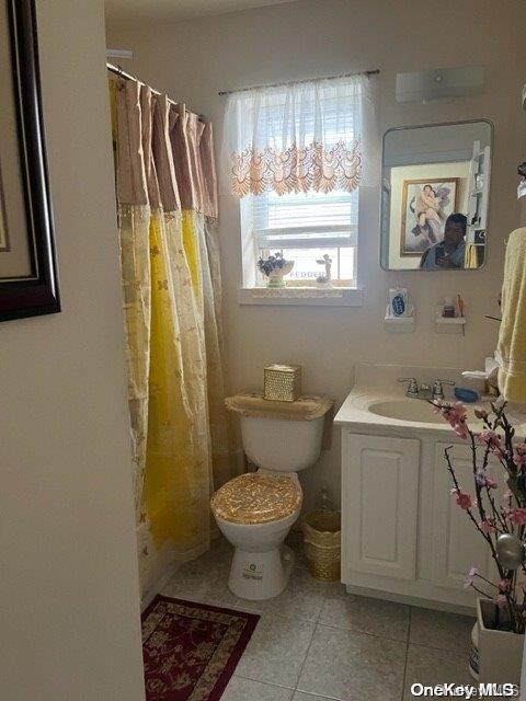 bathroom featuring toilet, vanity, tile patterned floors, and walk in shower