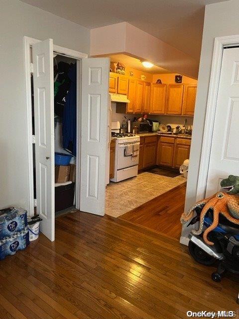 kitchen featuring white range with gas stovetop and hardwood / wood-style flooring