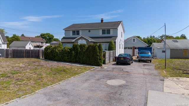 view of front of property with a garage, an outdoor structure, and a front lawn