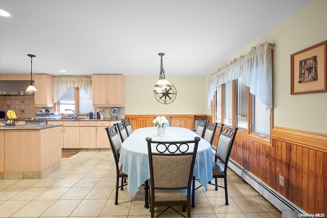 dining area featuring sink, a baseboard radiator, a chandelier, wooden walls, and light tile patterned floors