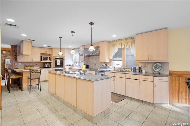 kitchen with tasteful backsplash, light brown cabinetry, stainless steel appliances, and a center island with sink