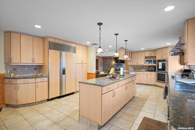 kitchen with wall chimney range hood, light brown cabinetry, decorative light fixtures, a kitchen island, and stainless steel appliances