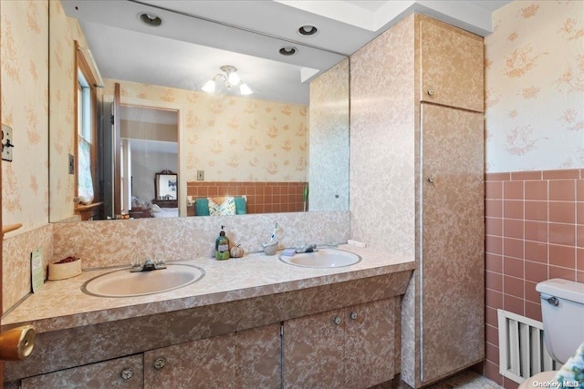 bathroom featuring vanity, toilet, and tile walls