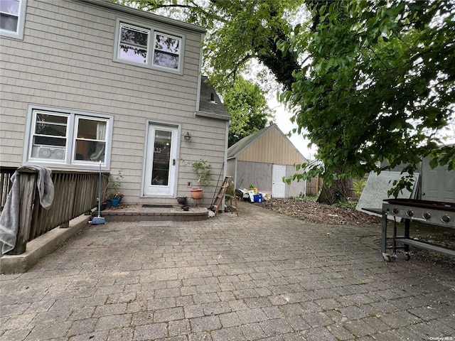 rear view of house with a storage unit and a patio