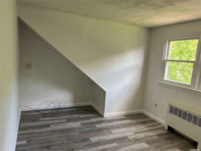 empty room with radiator heating unit and dark wood-type flooring