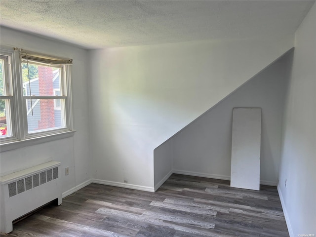 spare room with a textured ceiling, dark hardwood / wood-style floors, and radiator