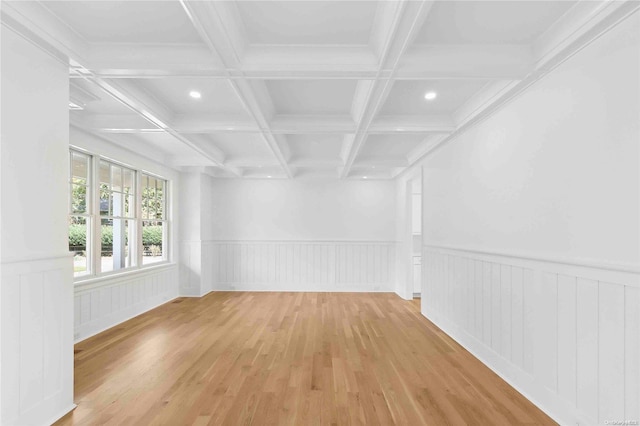 empty room featuring beamed ceiling, ornamental molding, light wood-type flooring, and coffered ceiling