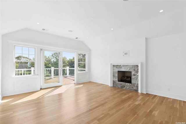 unfurnished living room with lofted ceiling, a healthy amount of sunlight, and light hardwood / wood-style floors