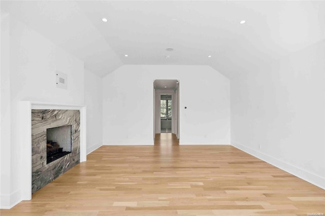 unfurnished living room featuring light wood-type flooring, lofted ceiling, and a premium fireplace