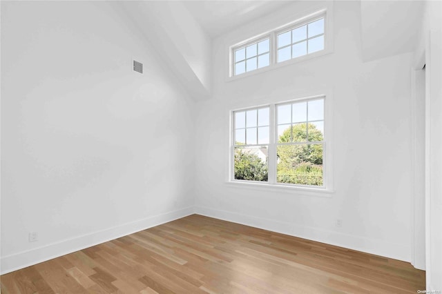 spare room with light hardwood / wood-style floors and a high ceiling