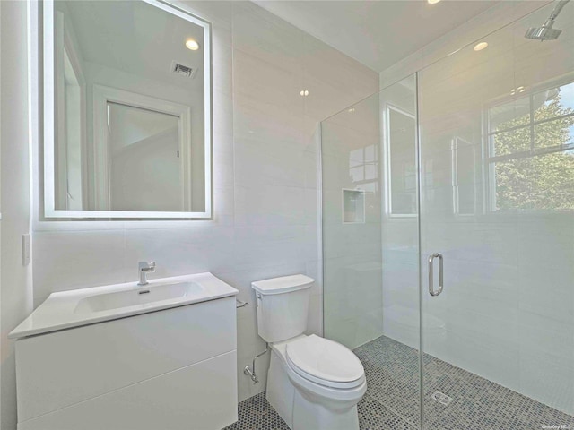 bathroom with tile patterned floors, an enclosed shower, toilet, vanity, and tile walls