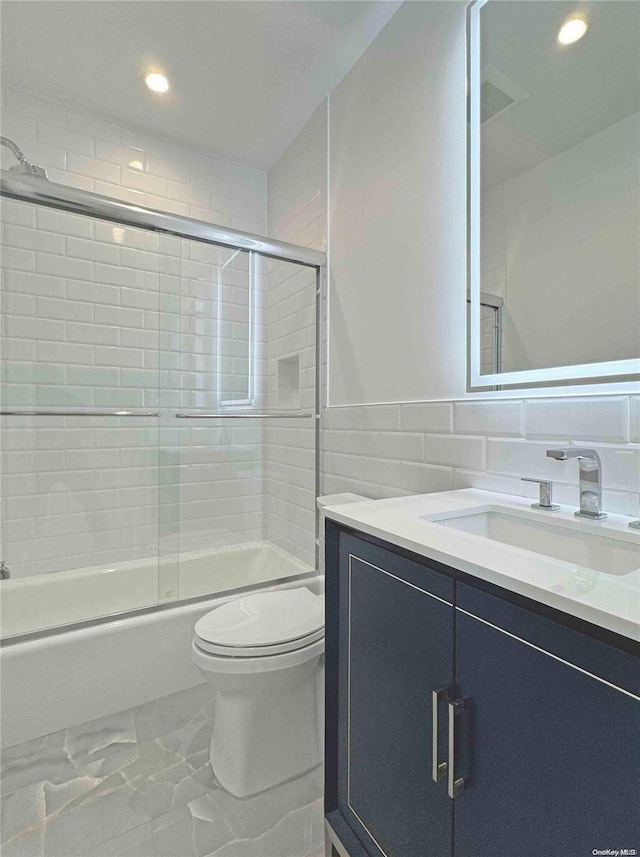 full bathroom with vanity, bath / shower combo with glass door, and toilet