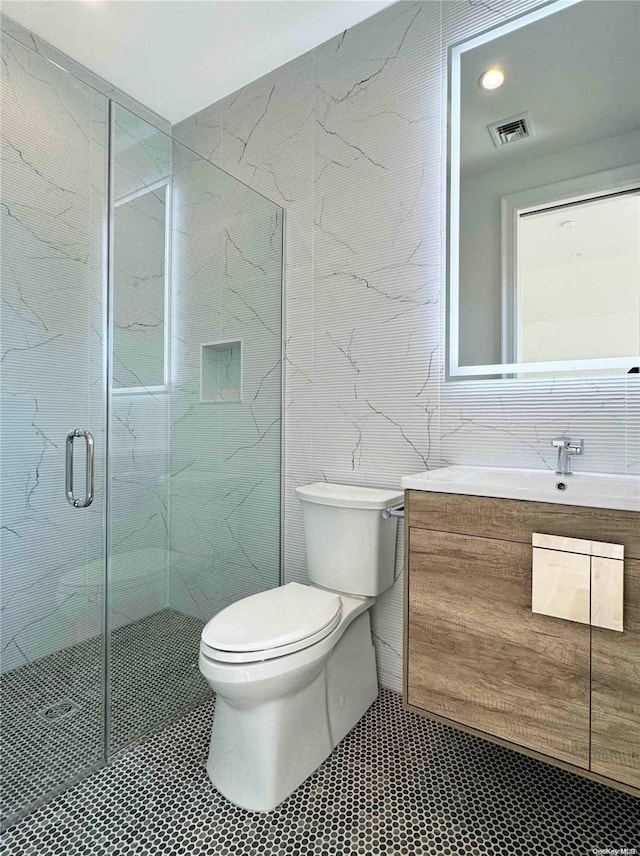 bathroom with tile patterned flooring, vanity, toilet, and a shower with door