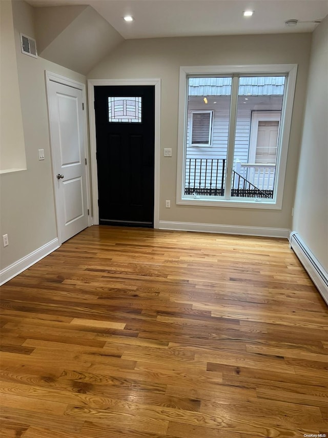 foyer featuring a baseboard heating unit, light wood-type flooring, and vaulted ceiling