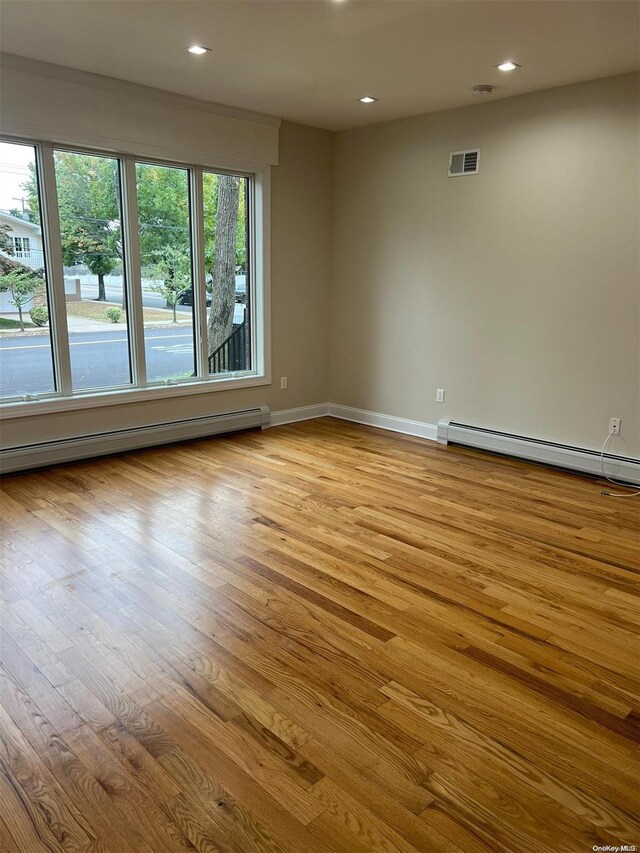 spare room with a baseboard radiator, light hardwood / wood-style flooring, and a wealth of natural light