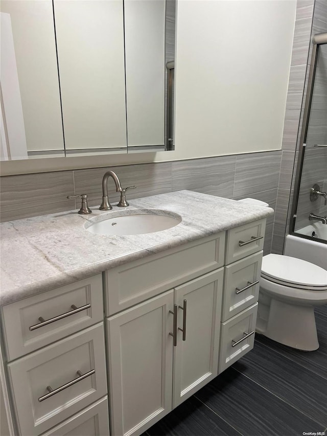 full bathroom with shower / tub combination, vanity, tile walls, and toilet