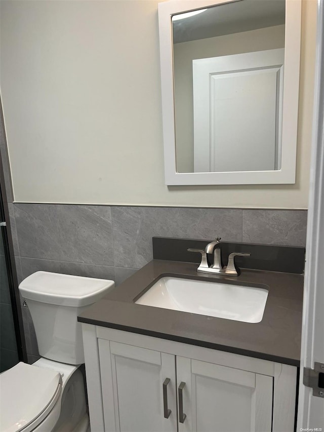 bathroom with vanity, toilet, and tile walls