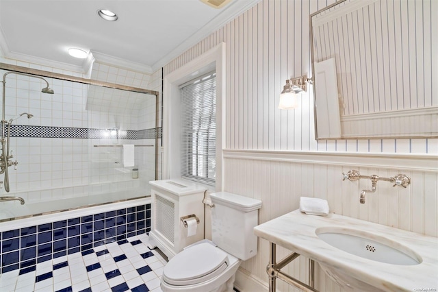 full bathroom featuring crown molding, sink, enclosed tub / shower combo, and toilet