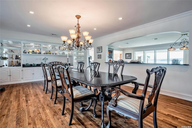 dining area with hardwood / wood-style flooring, an inviting chandelier, and crown molding