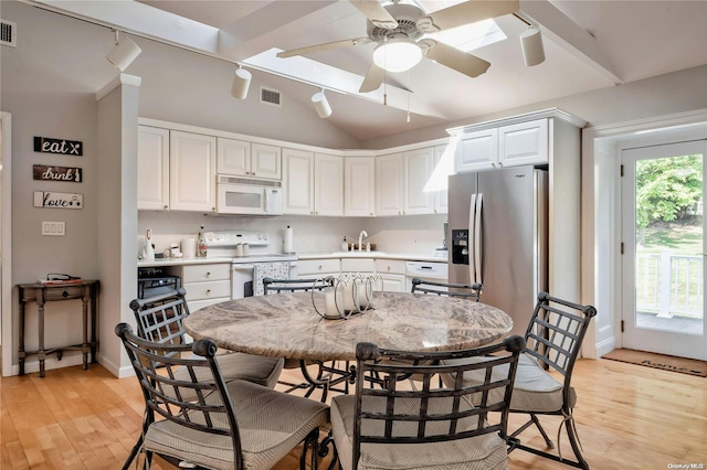 kitchen featuring white appliances, white cabinets, sink, vaulted ceiling with skylight, and light wood-type flooring