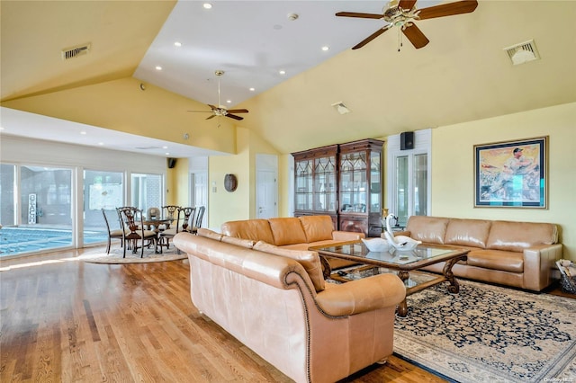 living room with light hardwood / wood-style floors, high vaulted ceiling, and ceiling fan