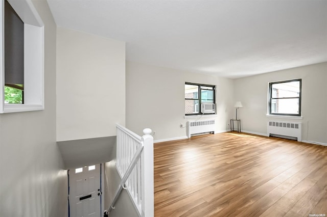 unfurnished living room featuring light hardwood / wood-style floors, radiator heating unit, and a wealth of natural light