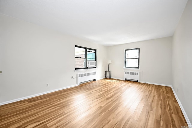 unfurnished living room featuring radiator, cooling unit, and light wood-type flooring