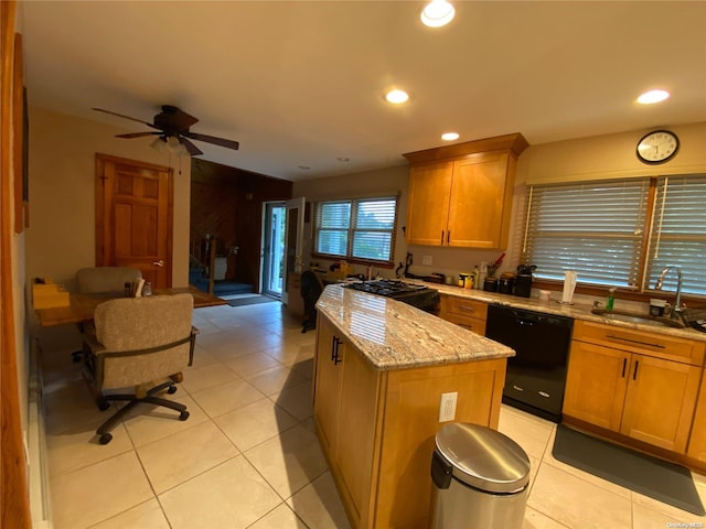 kitchen with ceiling fan, sink, a center island, black dishwasher, and light stone counters