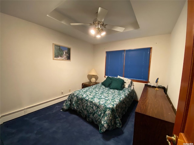 bedroom featuring ceiling fan, dark carpet, baseboard heating, and a tray ceiling