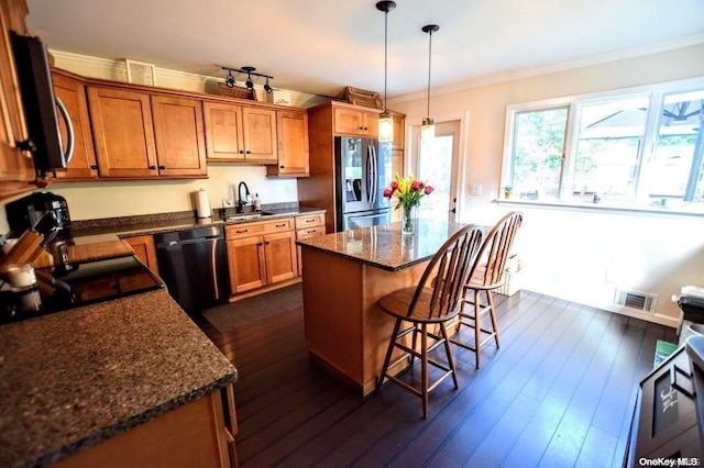 kitchen featuring appliances with stainless steel finishes, sink, a center island, dark hardwood / wood-style floors, and a breakfast bar area