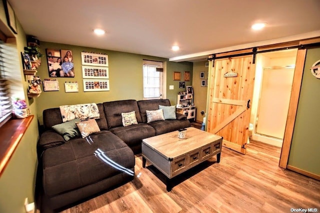 living room with a barn door and light wood-type flooring