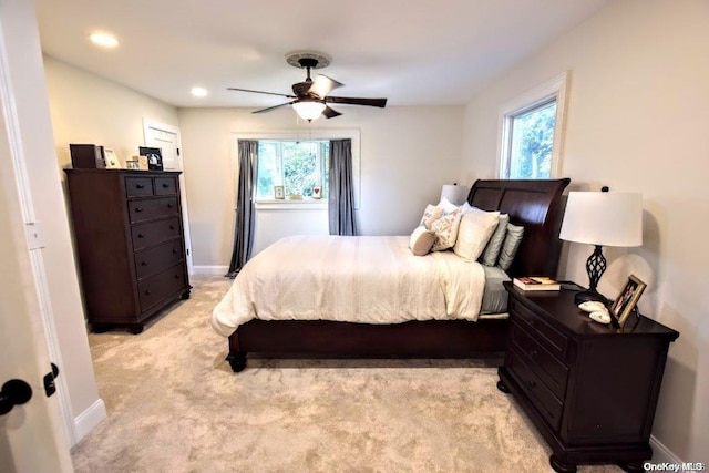 carpeted bedroom featuring multiple windows and ceiling fan