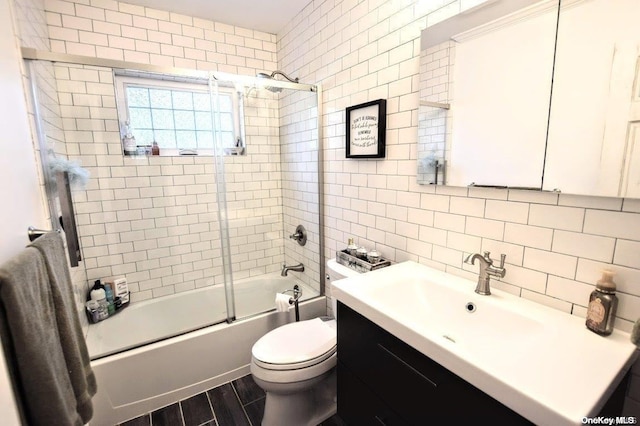 full bathroom with tasteful backsplash, toilet, shower / bath combination with glass door, vanity, and tile walls