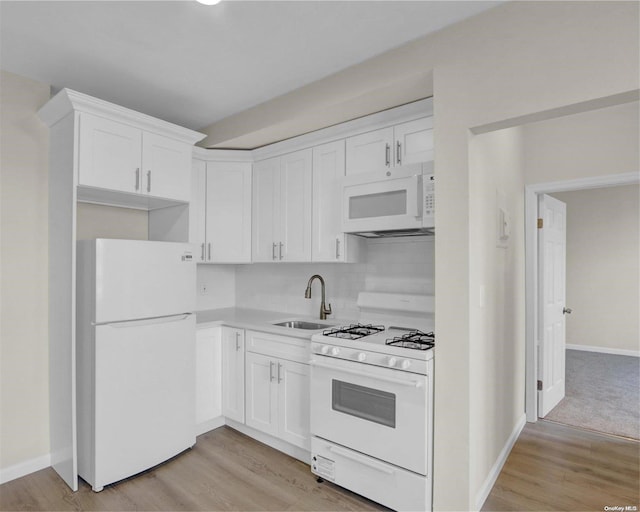 kitchen featuring white appliances, sink, light wood-type flooring, tasteful backsplash, and white cabinetry