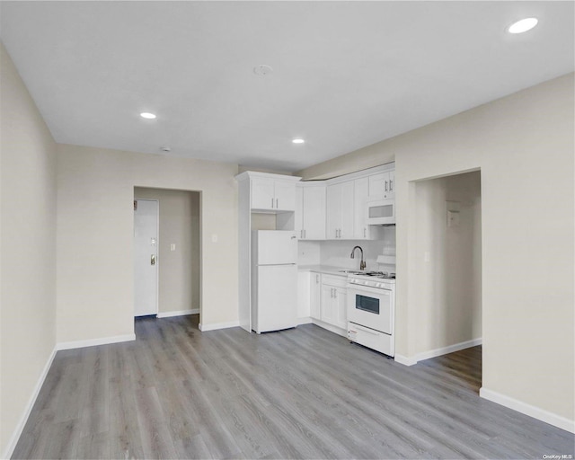 kitchen with light hardwood / wood-style floors, white cabinetry, white appliances, and sink