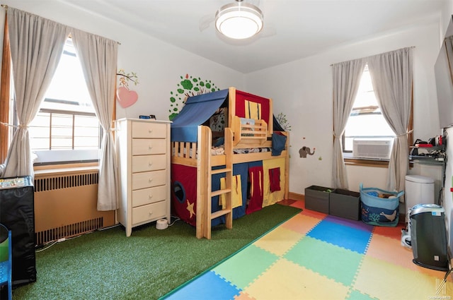 bedroom with radiator heating unit, carpet floors, and cooling unit