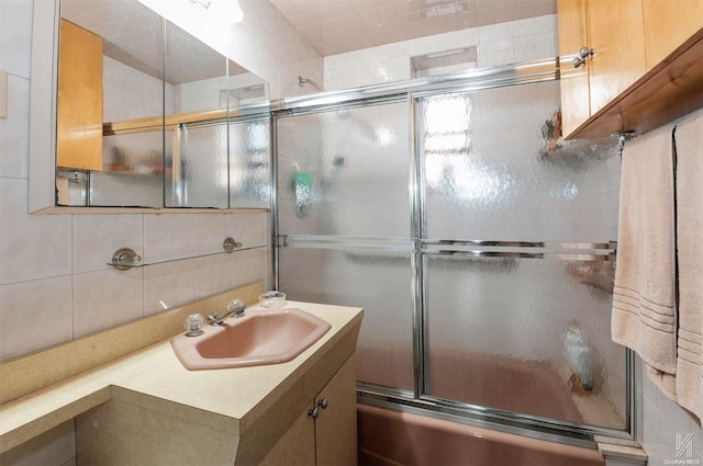 bathroom featuring tasteful backsplash, vanity, and bath / shower combo with glass door